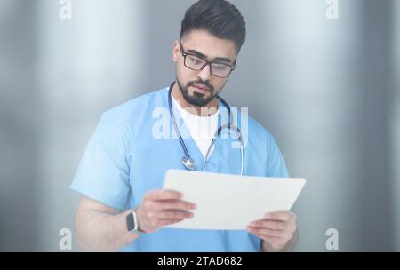 Arzt, der Papierkram erledigt, medizinische Dokumente am Arbeitsplatz überprüft. Stockfoto