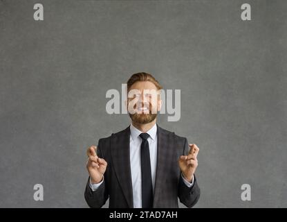 Geschäftsmann drückt die Daumen, glaubt an Glück und hofft auf das Beste Stockfoto