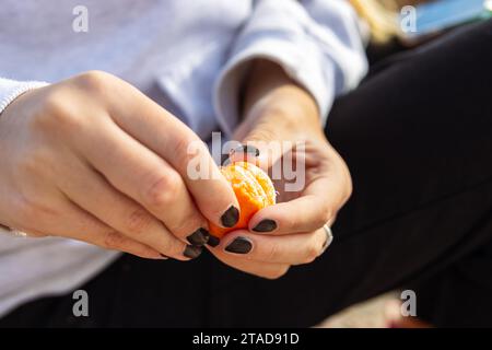 Schöne weibliche Hände eines Teenagers, der Mandarinen auf der Straße schält, mit Platz für Text Stockfoto