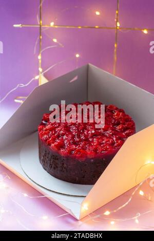Frischer Brownie mit Kirschen und Schokolade in einer Schachtel, Nahaufnahme. Köstlicher Schokoladenkuchen. Festlicher Hintergrund Stockfoto