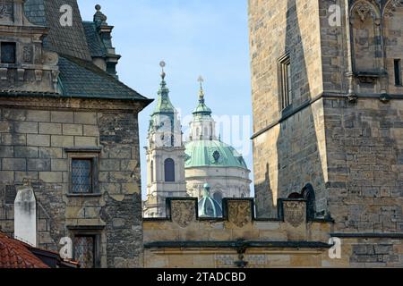 Nahaufnahme der Kuppel und des Glockenturms der St. Nikolaus-Kathedrale zwischen den Türmen der Karlsbrücke auf der Seite der Kleinstadt in Prag, Tschechische Republik. Stockfoto