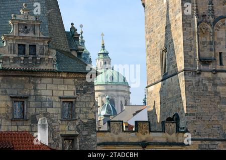 Nahaufnahme der Kuppel und des Glockenturms der St. Nikolaus-Kathedrale zwischen den Türmen der Karlsbrücke auf der Seite der Kleinstadt in Prag, Tschechische Republik. Stockfoto