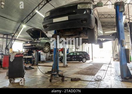Autos im Kfz-Reparaturzentrum. Moderne Autoreparaturstation mit einer großen Anzahl von Aufzügen und spezieller Ausrüstung für Diagnose und Service Stockfoto