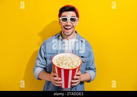 Foto von beeindruckt positiver Guy Wear Denim Jacke, die vr-Film sieht, der Popcorn isst isolierter gelber Hintergrund Stockfoto