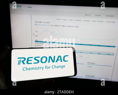 Person, die ein Mobiltelefon mit dem Logo des japanischen Chemieunternehmens Resonac vor der Business-Webseite hält. Schwerpunkt auf dem Display des Telefons. Stockfoto