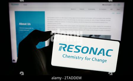 Person mit Smartphone und Logo des japanischen Chemieunternehmens Resonac vor der Website. Schwerpunkt auf dem Display des Telefons. Stockfoto