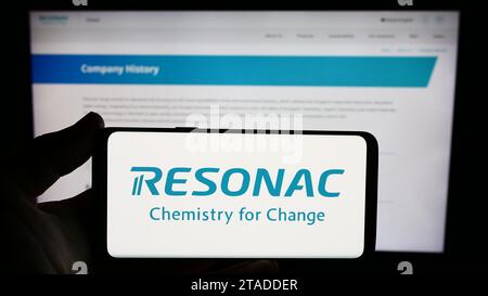 Person, die ein Handy mit dem Logo des japanischen Chemieunternehmens Resonac vor der Webseite hält. Schwerpunkt auf dem Display des Telefons. Stockfoto