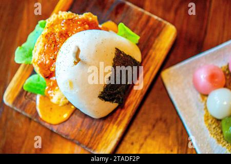 Ein Hochwinkel-Schuss eines asiatischen, gedämpften bao-Brötchen mit knusprigem gebratenem Huhn, Sauce und Salat. Stockfoto