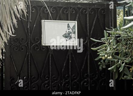 Verblasstes Schild mit der Aufschrift „Vorsicht vor dem Hund“ (auf Italienisch) am Gartenzaun Stockfoto