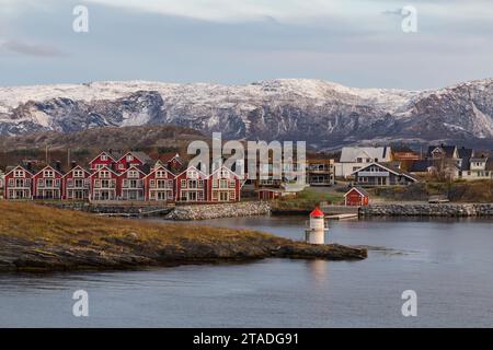 Farbenfrohe rote Häuser am Meer mit schneebedeckten Bergen dahinter in Bronnoysund, Norwegen, Skandinavien, Europa im Oktober Stockfoto