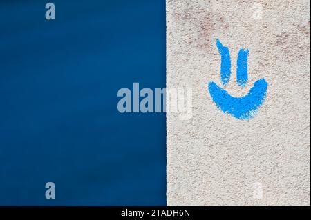 Positives Gefühl und lächelndes Konzept. Blaues lächelndes Emoji auf dem Gebäude und blauer Hintergrund. Negativer Kopierraum für die Textplatzierung. Stockfoto