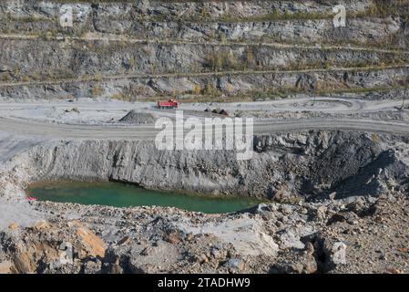 Ein Panoramablick auf einen Bergbaustandort mit schweren Maschinen und Arbeitern, die wertvolle Mineralien aus Gesteinen gewinnen, was die Karrieremöglichkeiten bei unterstreicht Stockfoto