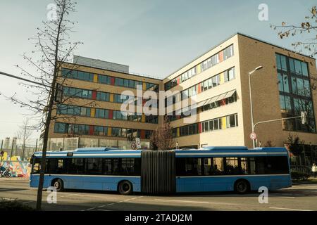 Öffentlicher Nahverkehr, Gelenkbus vor der kommunalen Berufsschule für Kinderbetreuung in München-Sendling Stockfoto