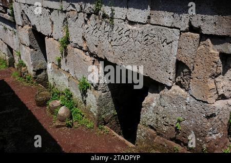 Inschriften in altitalischer Sprache und Schrift in etruskischer Sprache, die über den Grabeingängen in der Nekropole von Crocifisso del Tufo in Orvieto, Umbrien, Italien, in Sturze geschnitten wurden. Stockfoto