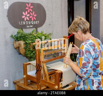 Aosta, Italien – 5. August 2023: Weaver benutzt einen traditionellen Webstuhl vor ihrem Laden. Stockfoto