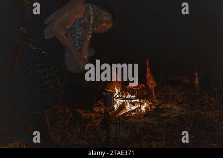 Tansania, WMA (Wildlife Management Area) von Randilen, Massai Camp und Grillen von Ziegenfleisch am Feuer Stockfoto