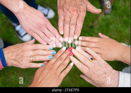 Konzept von Familie, alternder Gesellschaft oder Teamarbeit, Hände, die Einheit zeigen, indem sie Hände zusammenlegen, ältere, faltige Hände alter Menschen zusammen mit anderen jungen Menschen. Hochwertige Fotos Stockfoto
