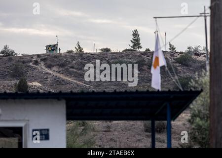 Nikosia, Nikosia, Zypern. November 2023 30. Die Flagge Zyperns ist auf einem unbemannten Außenposten der zyprischen Armee mit einem Außenposten der türkischen Armee im Hintergrund zu sehen. Die türkische Armee installierte vor zwei Tagen eine Kamera und die Flaggen der Türkei und der so genannten "Türkischen Republik Nordzypern" auf dem Dach eines verlassenen Hauses, bekannt als "Haus von Christalla", innerhalb der UN-Pufferzone. das offiziell das Gebiet der Republik Zypern ist, das der UNO aus friedenserhaltenden Gründen freiwillig zur Verfügung gestellt wird. Da es sich bei diesem Akt um einen Einbruch im Pufferzone-Status quo handelt, forderte die Republik Zypern die UNO-Truppen auf, entsprechend zu handeln Stockfoto