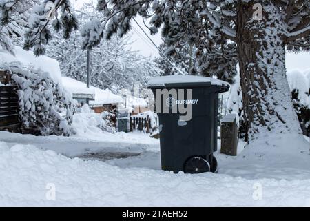 Burnaby, KANADA - 20. Dezember 2022 : Bild eines Mülleimers mit dem Logo der Stadt Burnaby. Winterszene mit Schnee auf dem Boden. Stockfoto