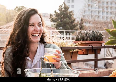 Glückliche junge Frau, die im Terrassenrestaurant draußen isst. Freunde, die Spaß bei der Dinnerparty draußen haben Stockfoto