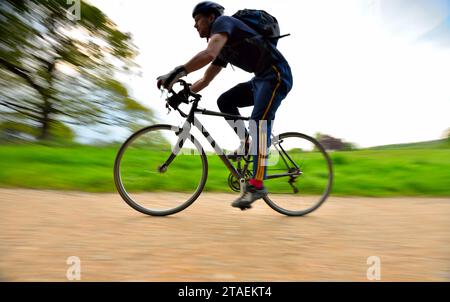 Ein Mann radelt auf einem der Schotterwege in Hampstead Heath im Norden Londons Stockfoto