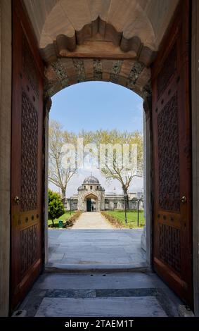 Ein lebhaftes Bild von zwei offenen Holztüren, die zu einem weitläufigen Gebäude der Suleymaniye-Moschee in Istanbul, Türkei, führen Stockfoto