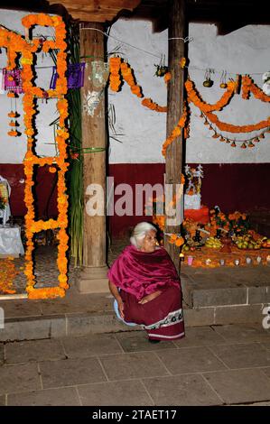 Santa Fe de la Laguna, Michoacan, Mexiko - 1. November 2023. Frau in heller traditioneller indischer Kleidung sitzt draußen am Tag des Todes in Mexiko Stockfoto