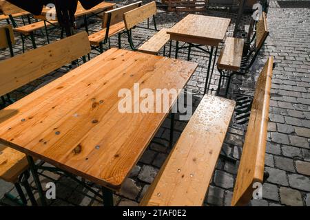 Holztische und -Stühle draußen im Garten unter dem Regen. Stockfoto