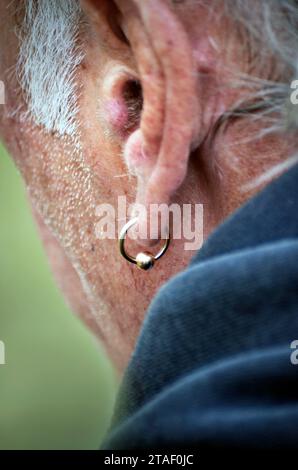 Alter unrasierter Mann mit goldenem Ohrring Stockfoto