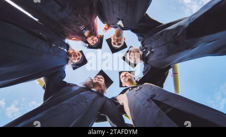 Studenten stehen in einem Kreis in schwarzen Gewändern. Stockfoto