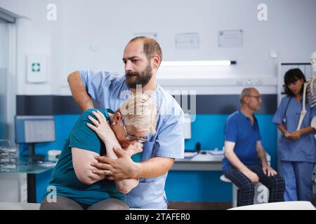 Ältere kaukasische Frau wird von einem Physiotherapeuten untersucht. Der Patient, der von Rückenbeschwerden heilt, wird unter Aufsicht einer Wirbelsäulendruckbeurteilung und einer Schmerzlinderung unterzogen. Stockfoto