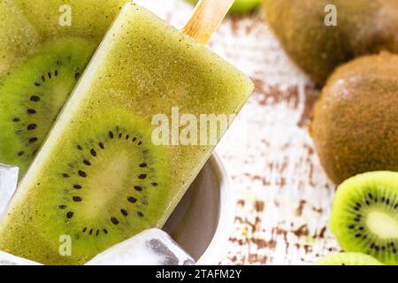 Schüssel mit Vanille und Kiwi-Joghurtkolben auf weißem rustikalem Holzhintergrund, ungesüßtes Eis, natürliche hausgemachte Stockfoto