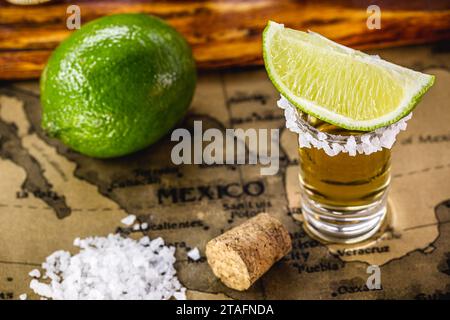 Gläser goldener Tequila, serviert mit Salz und Zitrone, auf einer alten Karte von mexiko Stockfoto