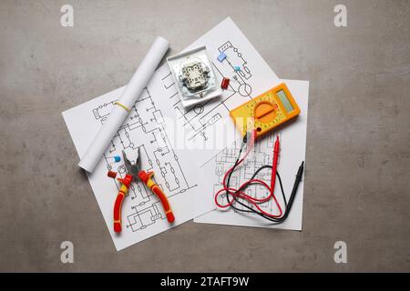 Schaltpläne, Digitalmultimeter, Zange und zerlegter Lichtschalter auf grauem Tisch, Draufsicht Stockfoto