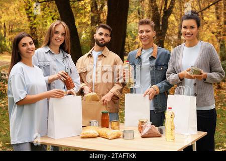 Porträt von Freiwilligen, die Lebensmittel am Tisch im Park packen Stockfoto