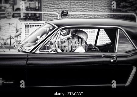 TORONTO, KANADA - 08 18 2018: Lachende Frau fährt einen Oldtimer 1966 Mustang Sportwagen, der vor lächelnden Männern während einer Open-Air-Autoshow stürmt Stockfoto