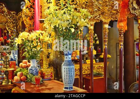 Detail eines Teils eines Altars in einem vietnamesischen buddhistischen Tempel in Hanoi, Vietnam. Zu den Gebetsopfern gehören Blumen, Obst und Getränkedosen Stockfoto