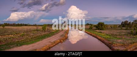 Panoramablick aus der Luft über einen Bewässerungskanal mit einem abendlichen Gewitter über dem Horizont in St. George in Queensland, Australien. Stockfoto