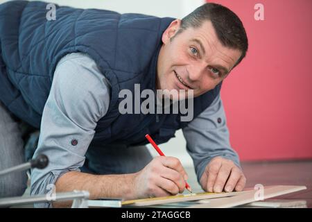 Zimmermann markiert gerade Linie auf Sperrholzblech Stockfoto