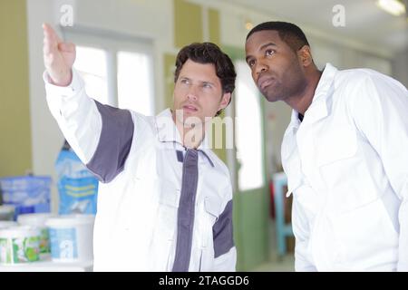 Der Arbeiter gibt vor zwei Malern die Daumen hoch Stockfoto