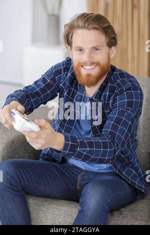 Ein Mann zu Hause, der Videospielkontrollen hält Stockfoto