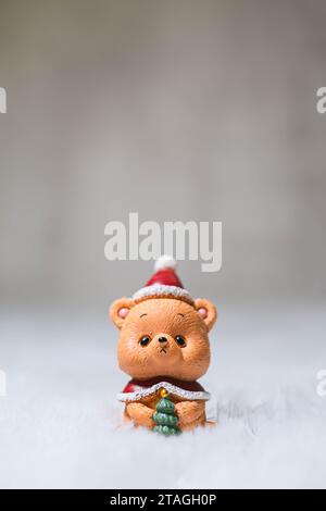 Das kleine und süße Teddybär-Spielzeug trägt einen Weihnachtsmann-Hut und eine Strickjacke mit Bokeh-Hintergrund. Winter- und Weihnachtskonzept. Weihnachtsdekoration. Stockfoto