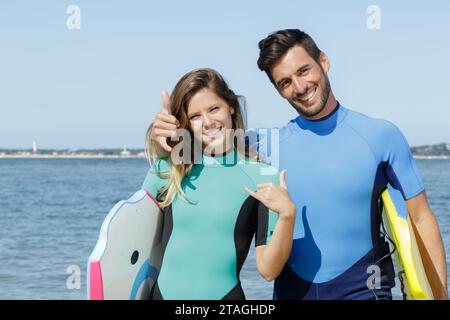 Glückliches Paar, das Surfschilder zeigt Stockfoto