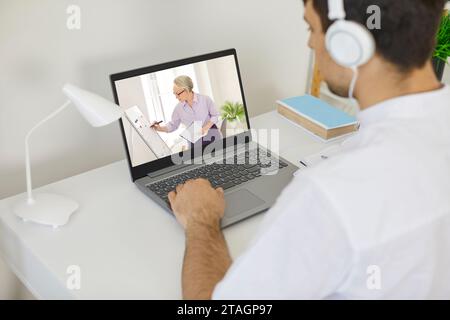 Junger Mann, der am Laptop sitzt, Online-Unterricht hat oder Videovorlesungen ansieht Stockfoto