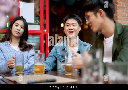 Eine Gruppe glücklicher junger asiatischer Freunde macht es Spaß, gemeinsam an einer Bar Bier zu trinken und zu unterhalten. Freundschaft, Lebensstil, Happy Moment, Freunde treffen Stockfoto