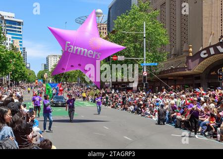 Die Farmers Christmas Parade in Auckland, Neuseeland. Das Logo des Bauernkaufhauses auf einem sternförmigen Ballon, der von Freiwilligen gezogen wurde Stockfoto