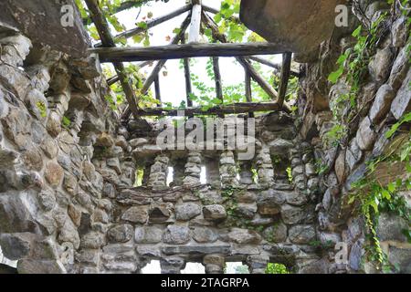 Überreste eines alten eingestürzten Holzdachs auf einem verlassenen rustikalen Steinpavillon auf dem Gelände des Gillette Castle State Park in East Haddam, Connecticut. Stockfoto