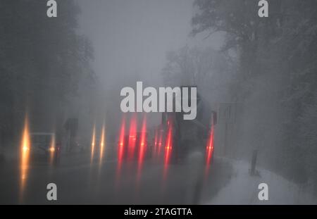 Stuttgart, Deutschland. Dezember 2023. Die Heckleuchten der Fahrzeuge leuchten während der morgendlichen Hauptverkehrszeit durch eine schneebedeckte Windschutzscheibe. Gegen Ende dieser Woche wird es in den meisten Teilen Deutschlands frostig bleiben. Auch rutschige Straßen müssen immer wieder erwartet werden. „Eiskalter Regen ist in weiten Teilen Deutschlands immer noch ein Problem“, sagte ein Meteorologe vom Deutschen Wetterdienst (DWD) am Freitagmorgen. Die DWD gab für einen großen Teil Deutschlands eine offizielle glatte Straßenwarnung aus, die bis Freitag 12,00 Uhr gültig ist. Quelle: Bernd Weißbrod/dpa/Alamy Live News Stockfoto