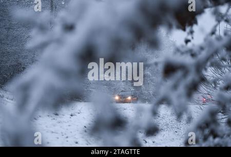 Stuttgart, Deutschland. Dezember 2023. Fahrzeuge fahren während der morgendlichen Rushhour durch ein schneebedecktes Waldgebiet in Stuttgart. Gegen Ende der Woche wird es in den meisten Teilen Deutschlands frostig bleiben. Auch rutschige Straßen müssen immer wieder erwartet werden. „Eiskalter Regen ist in weiten Teilen Deutschlands immer noch ein Problem“, sagte ein Meteorologe vom Deutschen Wetterdienst (DWD) am Freitagmorgen. Die DWD gab für den größten Teil Deutschlands eine offizielle glatte Straßenwarnung aus, die bis Freitag 12:00 Uhr gültig ist. Quelle: Bernd Weißbrod/dpa/Alamy Live News Stockfoto