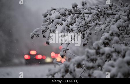 Stuttgart, Deutschland. Dezember 2023. Die Rücklichter der Fahrzeuge leuchten im morgendlichen Rush Hour-Verkehr auf einer Straße durch ein schneebedecktes Waldgebiet in Stuttgart. Gegen Ende dieser Woche wird es in den meisten Teilen Deutschlands frostig bleiben. Immer wieder ist mit rutschigen Straßen zu rechnen. „Eiskalter Regen ist in weiten Teilen Deutschlands immer noch ein Problem“, sagte ein Meteorologe vom Deutschen Wetterdienst (DWD) am Freitagmorgen. Die DWD gab für den größten Teil Deutschlands eine offizielle glatte Straßenwarnung aus, die bis Freitag 12:00 Uhr gültig ist. Quelle: Bernd Weißbrod/dpa/Alamy Live News Stockfoto